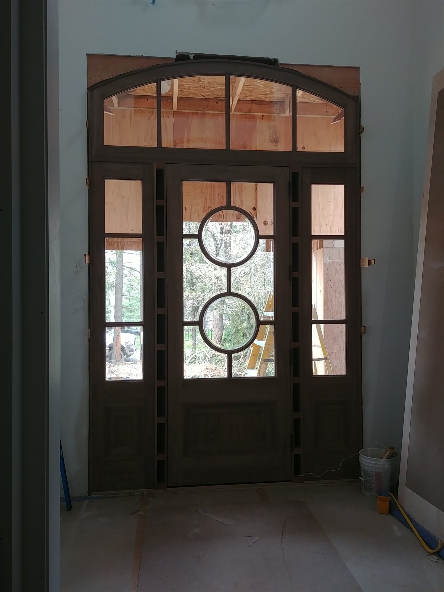 Custom arched entry door with paired leaded-glass oculus lights